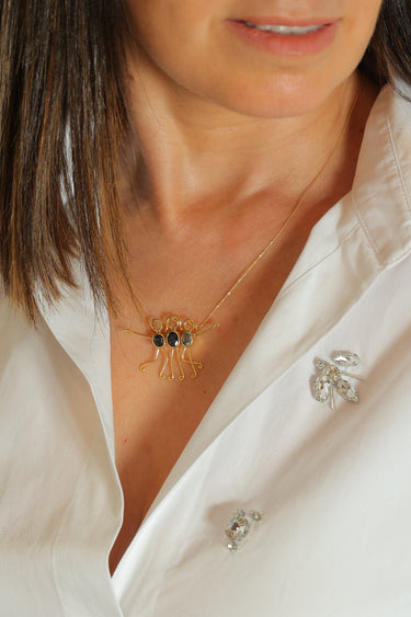 Elegant gold necklace with a sapphire gemstone, symbolizing family love and strength.