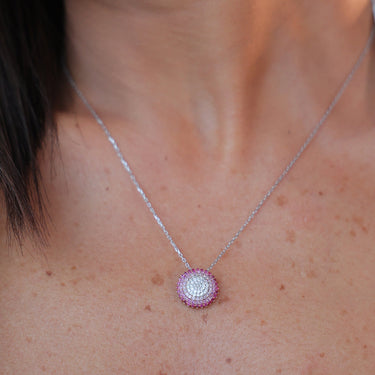 Elegant 18k gold necklace with a disk pendant featuring pink sapphires and a white diamond.