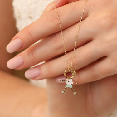 Gold jewelry charm featuring a boy figure, crafted in 18k gold with enamel.