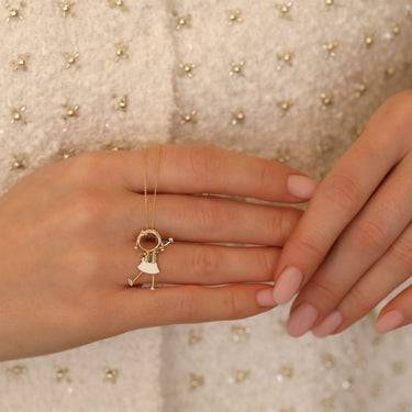Gold jewelry piece featuring a charming girl with raised hand, crafted from 18k gold and enamel.