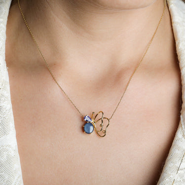LUMINUS WINGS NECKLACE featuring blue sapphire and tanzanite stones in 18k gold on a model.