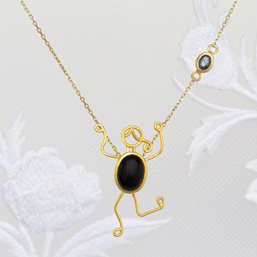 18k gold necklace with black onyx and blue sapphire character pendant.