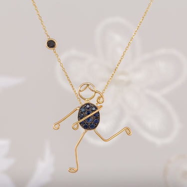 Handmade 18k gold necklace with blue sapphire and black diamond character design.